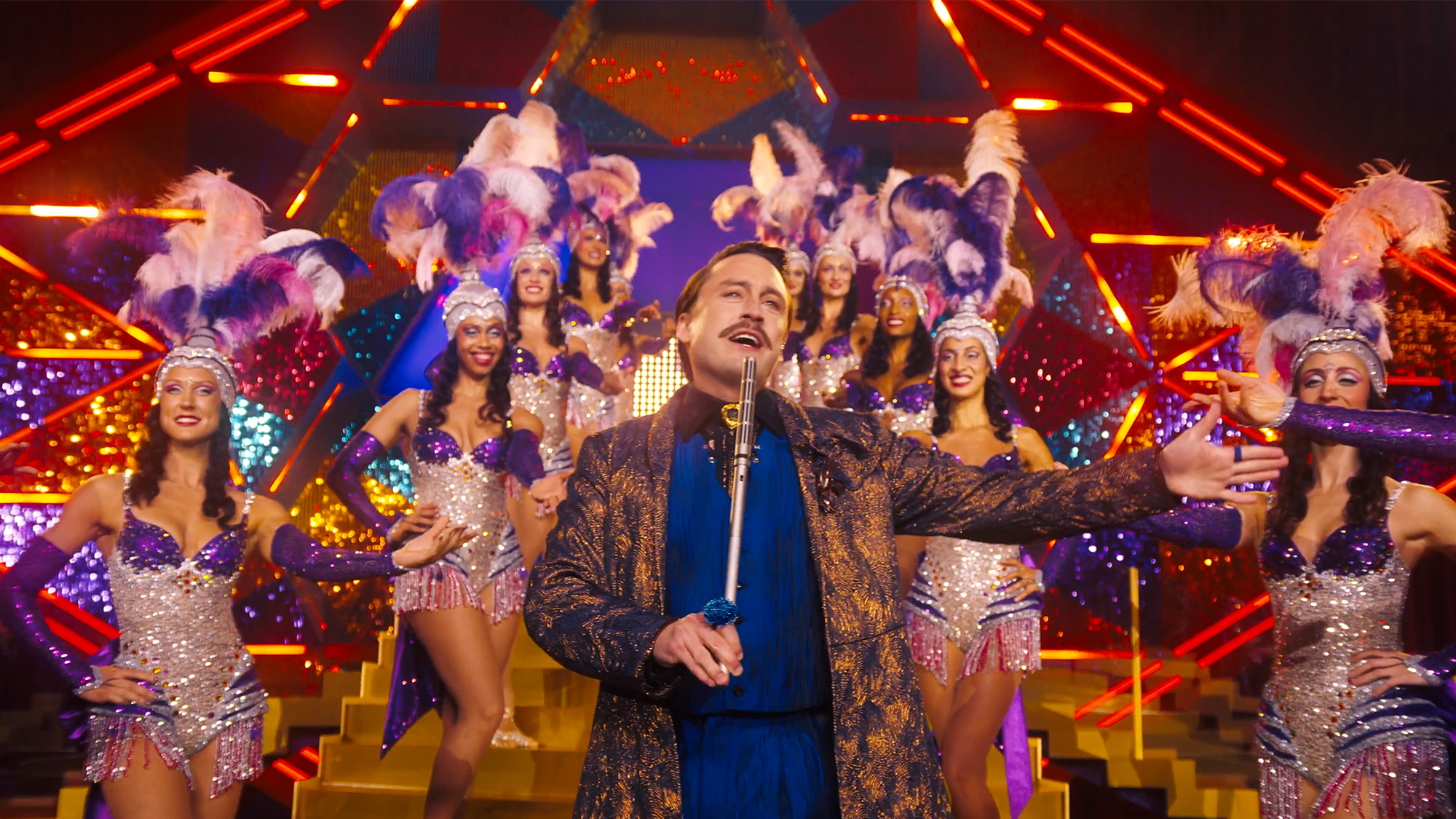 Kiernan Culken in front of showgirls in Sunrise on the Reaping