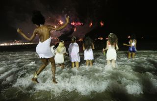 Five friends wearing white enter the waves at Copacabana Beach in Brazil on New Year's Eve