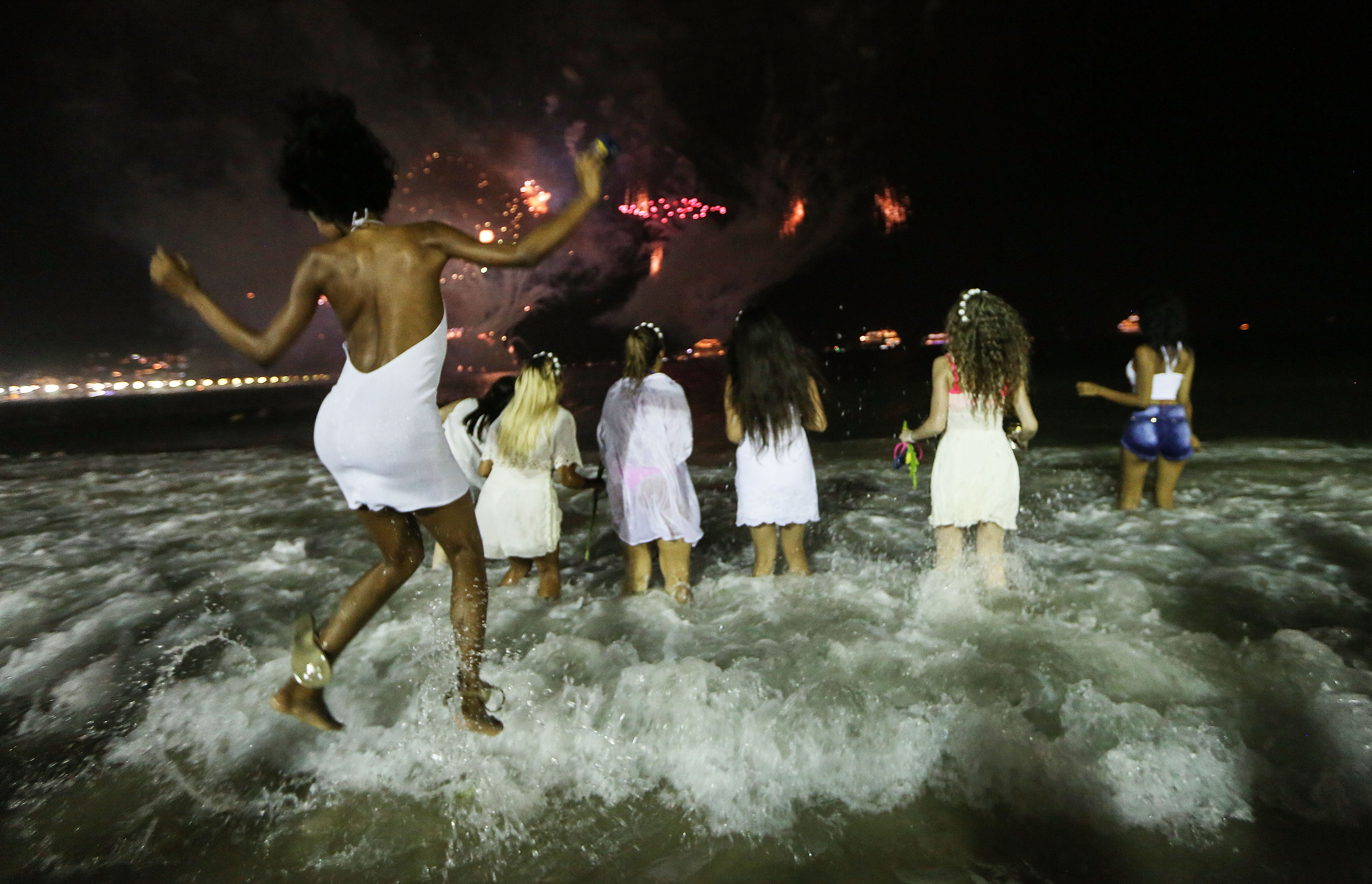 Five friends wearing white enter the waves at Copacabana Beach in Brazil on New Year's Eve