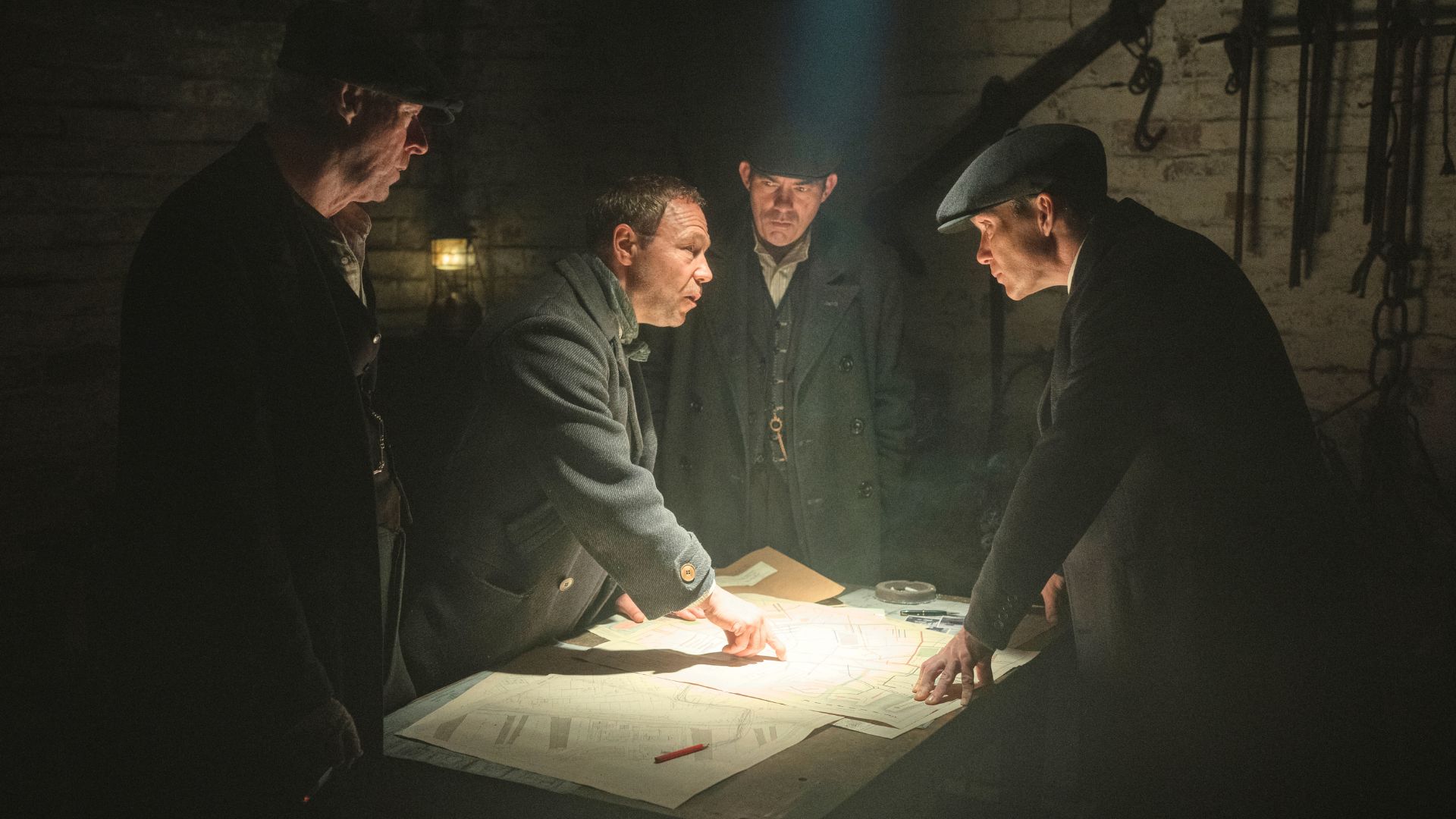 يتجمع فريق البيكي بلايندرز حول طاولة ذات إضاءة خافتة