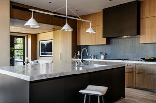 a wooden kitchen with a black island with a marble countertop