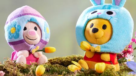 Piglet and Winnie the Pooh in Easter outfits on a mossy log