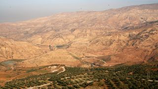 an aerial view of a hilly desert landscape with some greenery