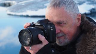 Man holding a Nikon D780 in front of an icy lake