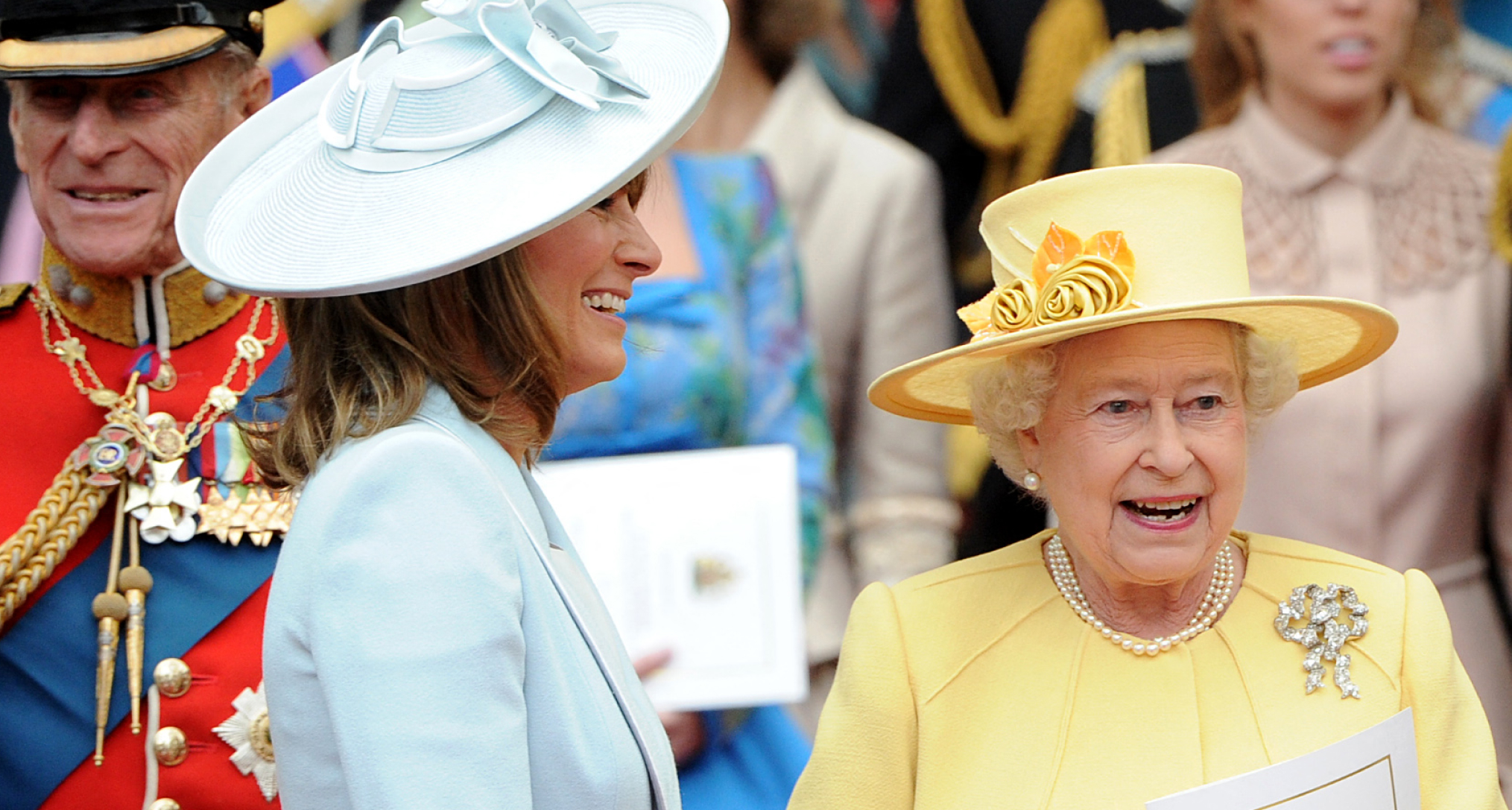 Carole Middleton wearing a blue hat and coat talking to Queen Elizabeth at William and Kate's wedding