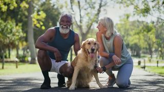 Man and woman laughing in park with golden retriever