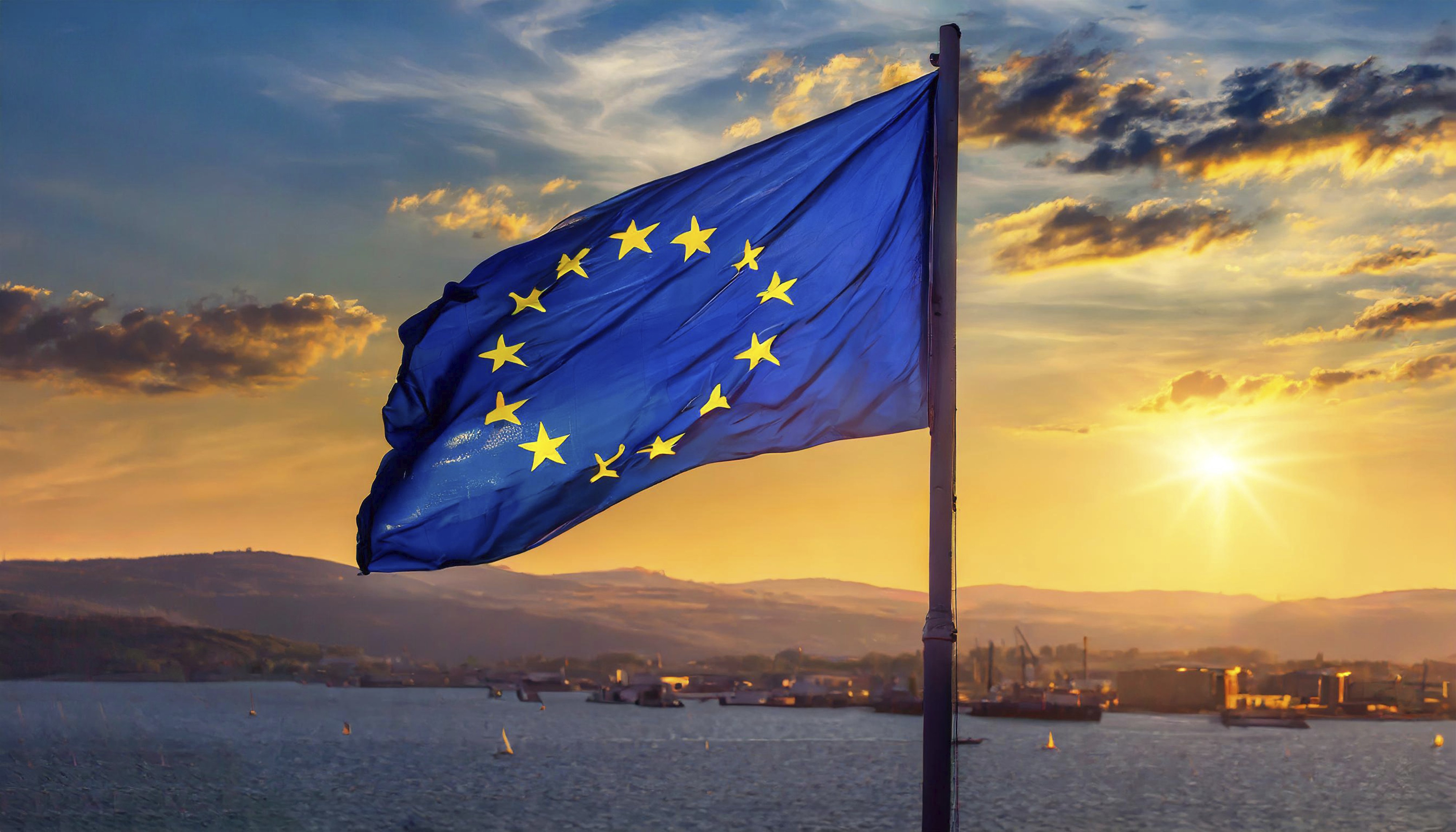 A photo of an E.U. flag in the wind at sunset.