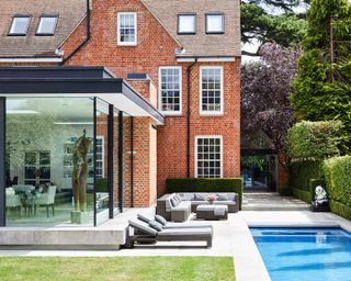 exterior of red brick house with pool and glass extension