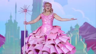 Ashley Eckstein wearing a pink paper dress to sing Wicked at Her Universe Fashion Show 2025