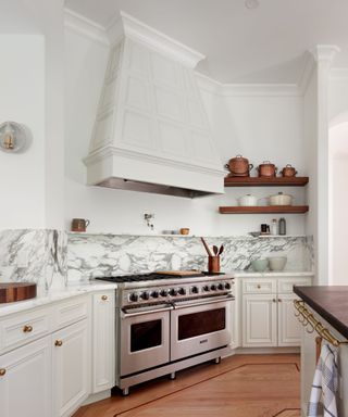kitchen with white cabinets and range cooker with marble backsplash and black island countertop