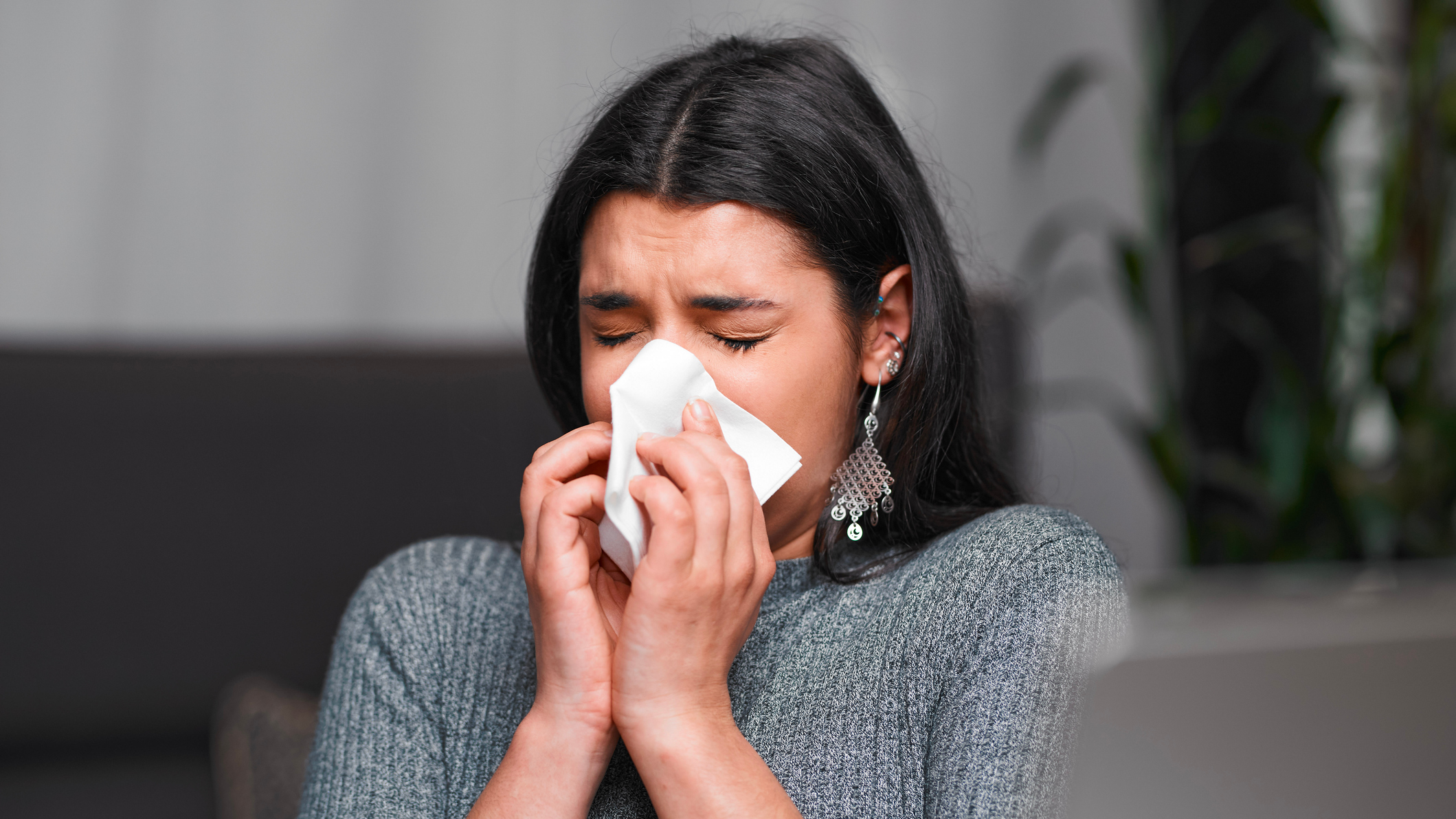 A woman blowing her nose with a tissue