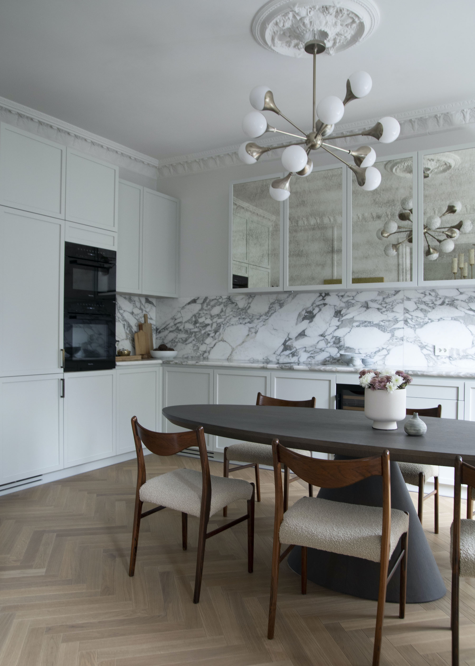 kitchen with table and chandelier hanging above the table. There are also glass cabinets.