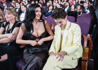 Kylie Jenner wearing a low-cut black gown sitting next to Timothee Chalamet, wearing a yellow suit, at the 2025 Oscars