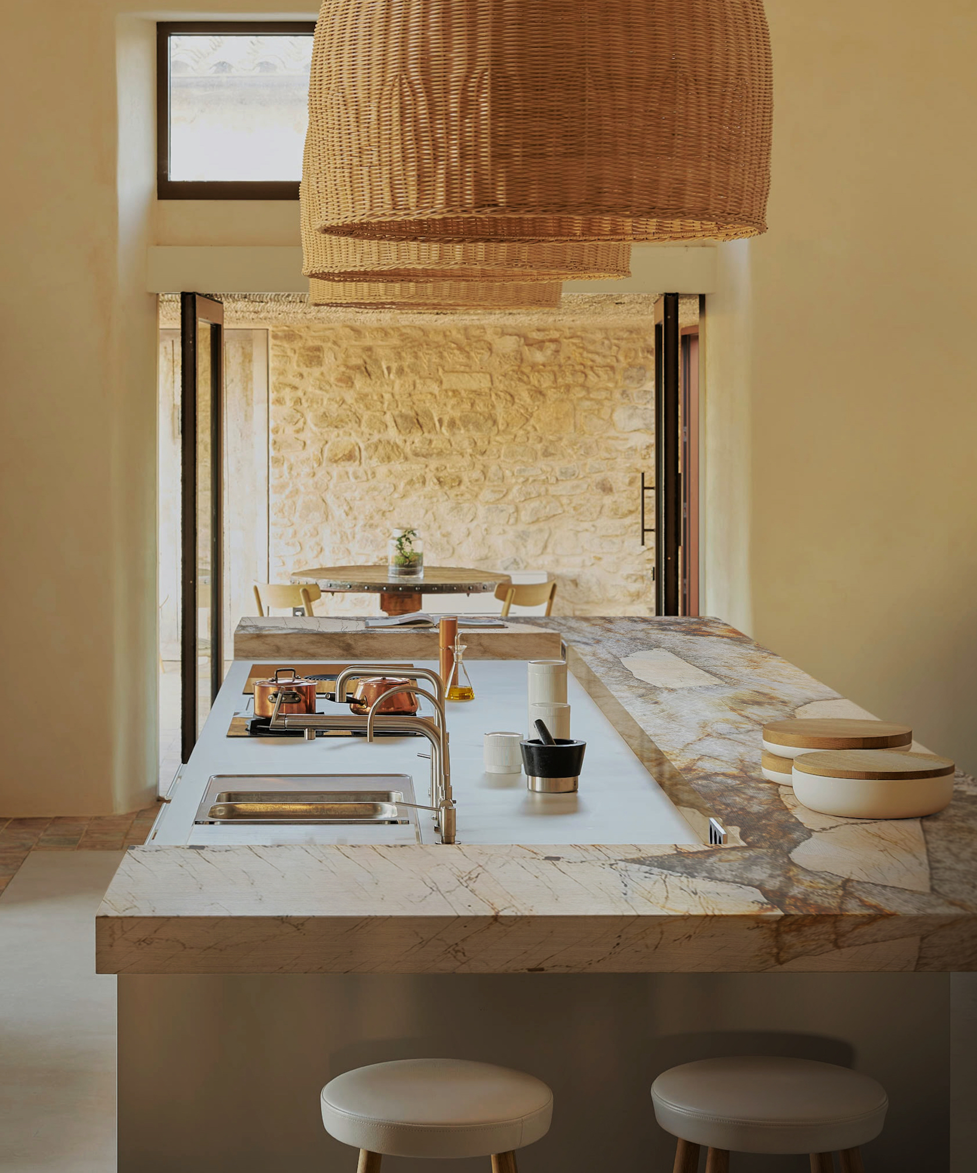 kitchen island with taps and sink and large rattan pendants