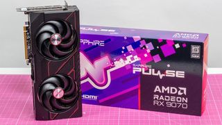 An AMD Radeon RX 9070 on a desk next to its retail packaging seen from a slightly elevated angle