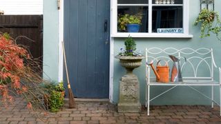 Painted walls and door in garden with bench and broom in front