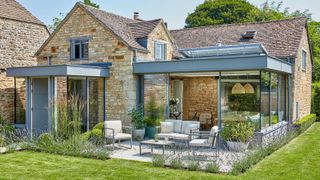 stone cottage with modern extension leading out to a patio with outdoor seating