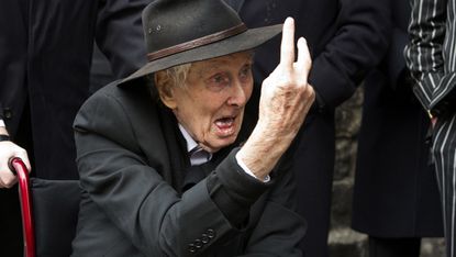Great Train Robber Ronnie Biggs gestures to photographers at the funeral of Bruce Reynolds, at the church of St Bartholomew the Great in London March 20, 2013. Reynolds, the key planner behin