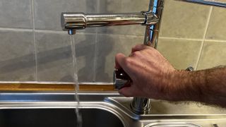 A hand is turning on the Fohen Flex's boiling water function, which is pouring from a spout