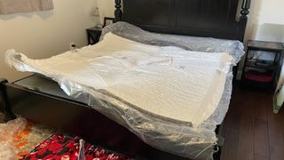 Puffy Cloud mattress during setup, wrapped in plastic on our tester's king bed frame