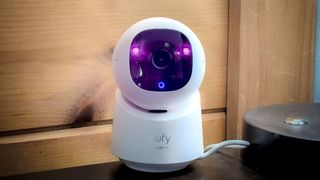 Eufy Security Indoor Cam C220 on a table next to a lamp.