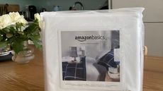 A close up shot of the Amazon Basics Mattress Protector on a table next to a vase with flowers