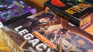 Pandemic Legacy Season 0, Disney Lorcana: Deep Trouble, and Betrayal at House on the Hill 3rd Edition on a wooden table, against a black background