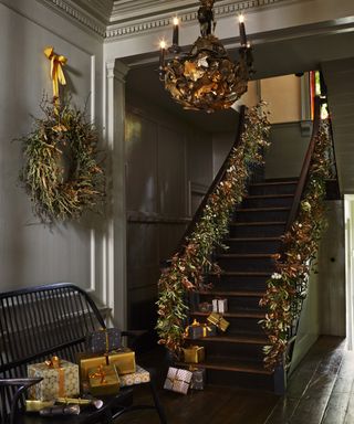 Christmas stair decor ideas with a foliage and dark gold garland, wreath and gold presents