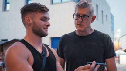 Louis Theroux interviewing a man outside looking at a mobile phone