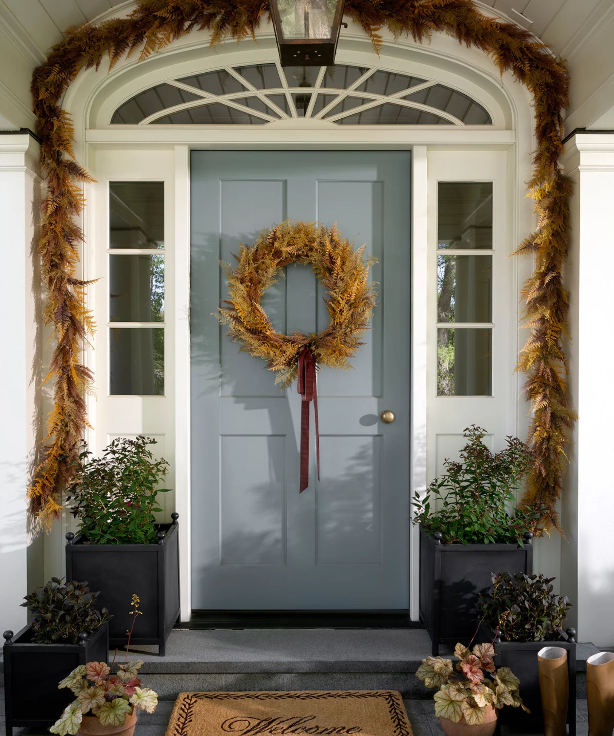 Fall porch with a pale gray door decorated with a fall wreath and fall garland