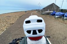 toddler sat on a kids ride shotgun seat with dad riding along a seafront setting. 