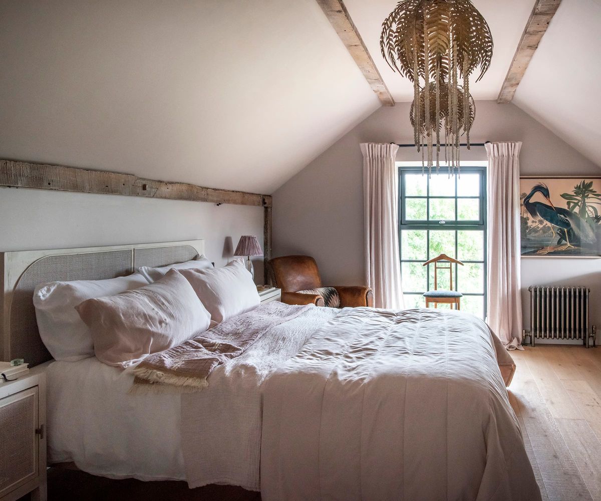 An upstairs bedroom with wooden beams and wooden flooring