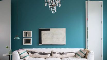 A living room with teal walls and white sofa
