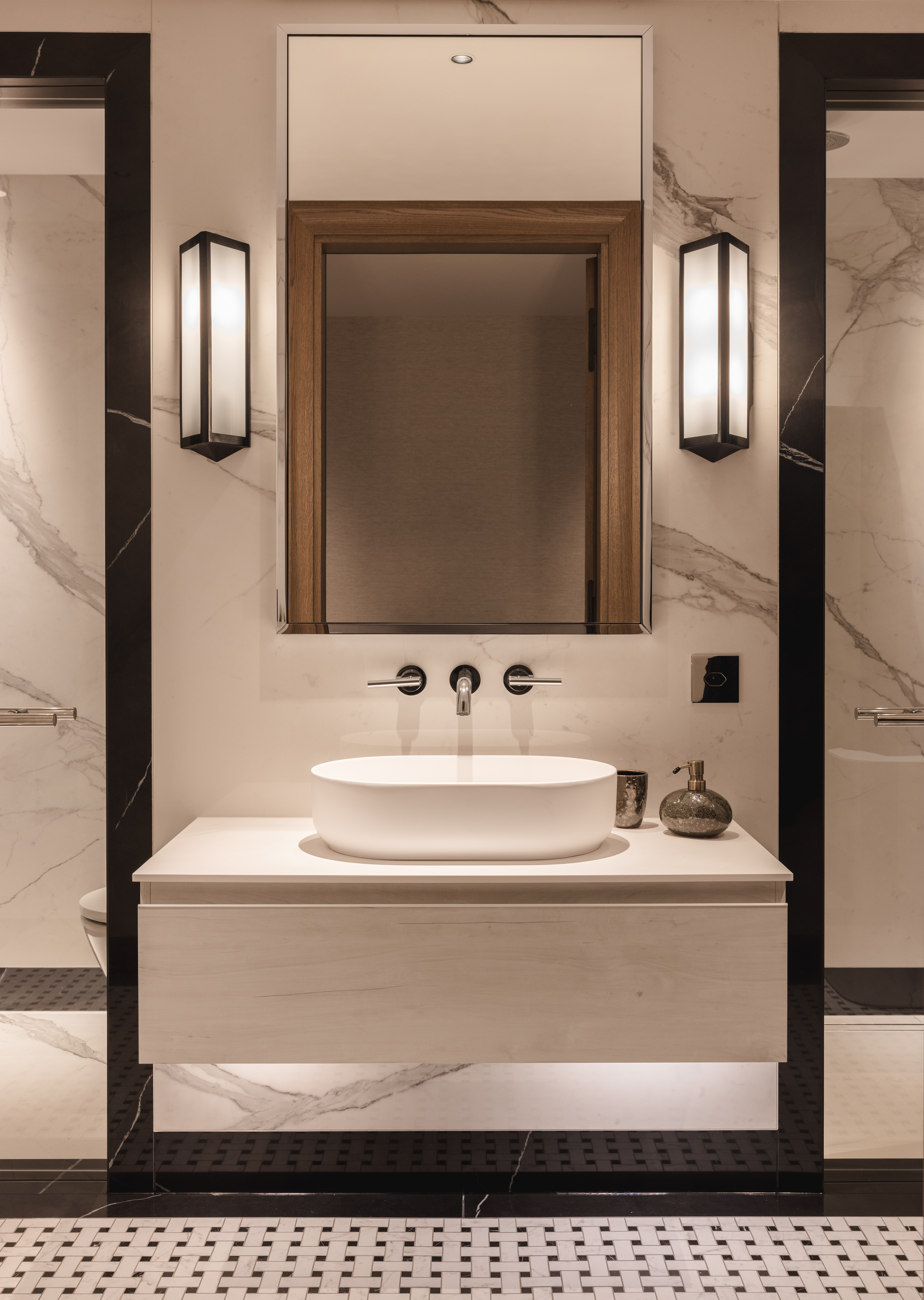 sink area in a modern bathroom with two door either side, both framed by black marble architraves