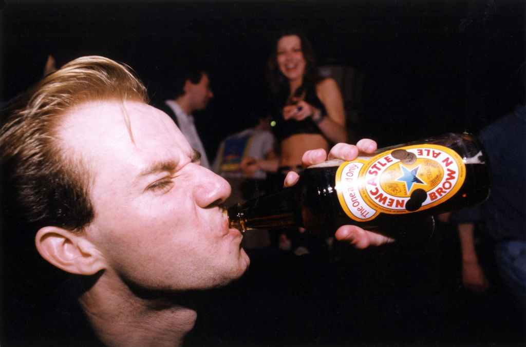 A young man drinking Newcastle Brown Ale on a night out in the North East of England, circa 1995.