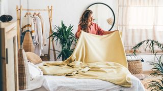 A woman changes her bedsheets on a sunny day