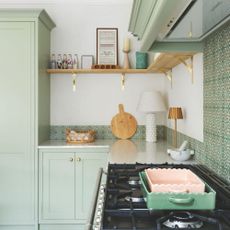 White painted kitchen with green tiles on the wall and green kitchen cupboards
