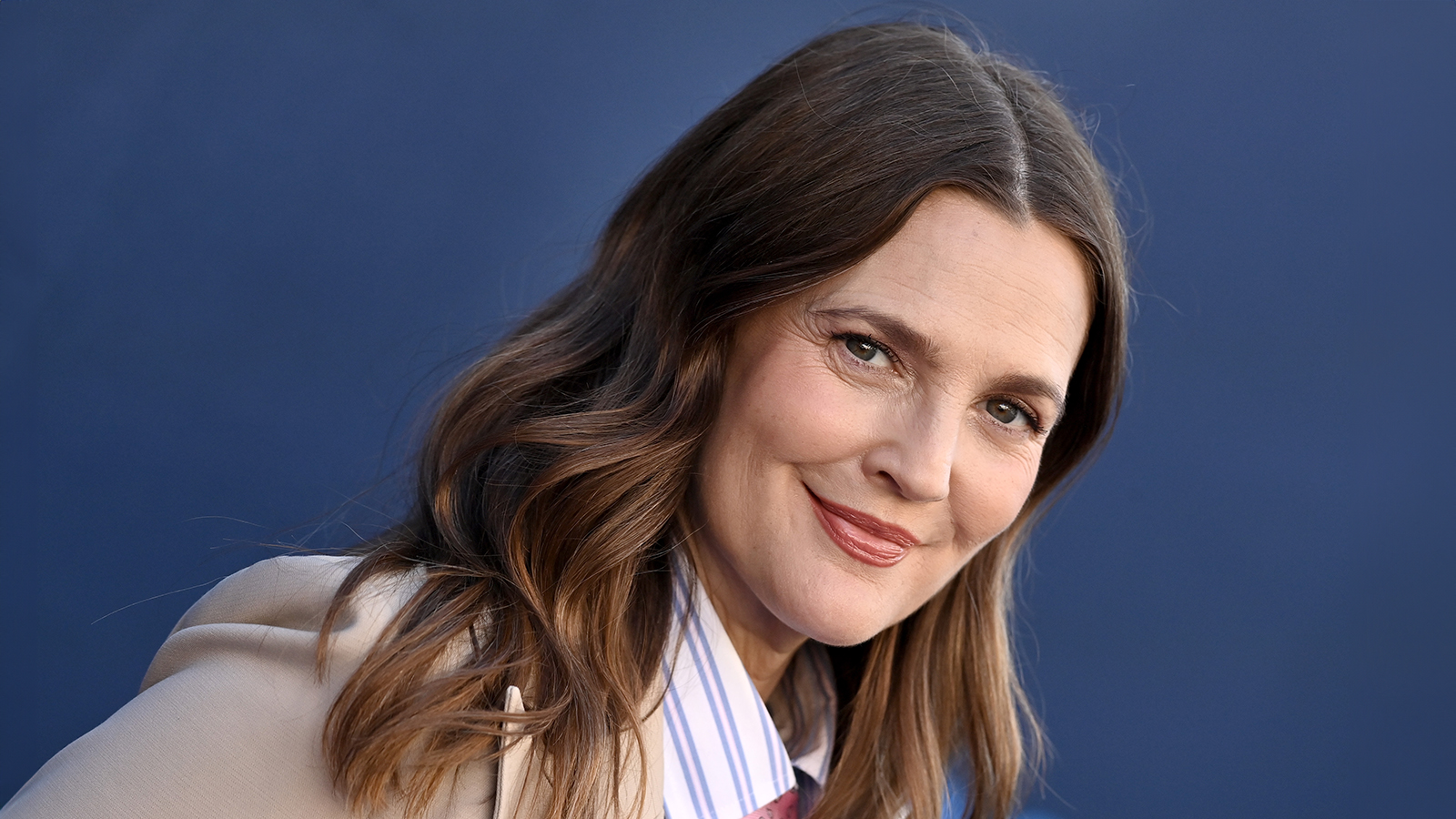 Drew Barrymore wearing suit in front of blue background