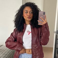 Influencer wears a burgundy leather jacket.