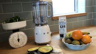 Smeg BLF01PBUK blender on a kitchen countertop with fruit and oat milk