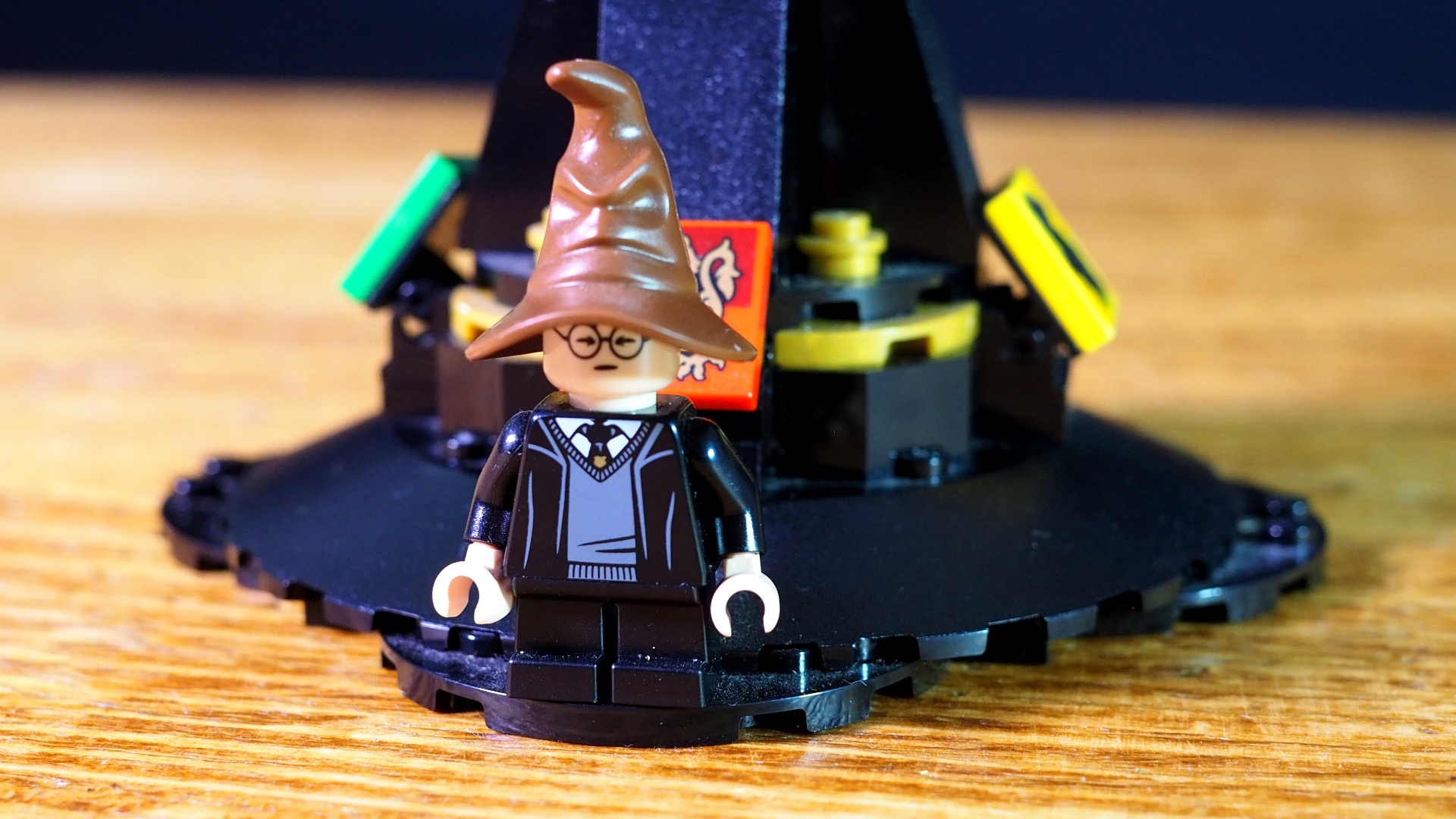 The Harry minifigure and Lego Talking Sorting Hat stand on a wooden table