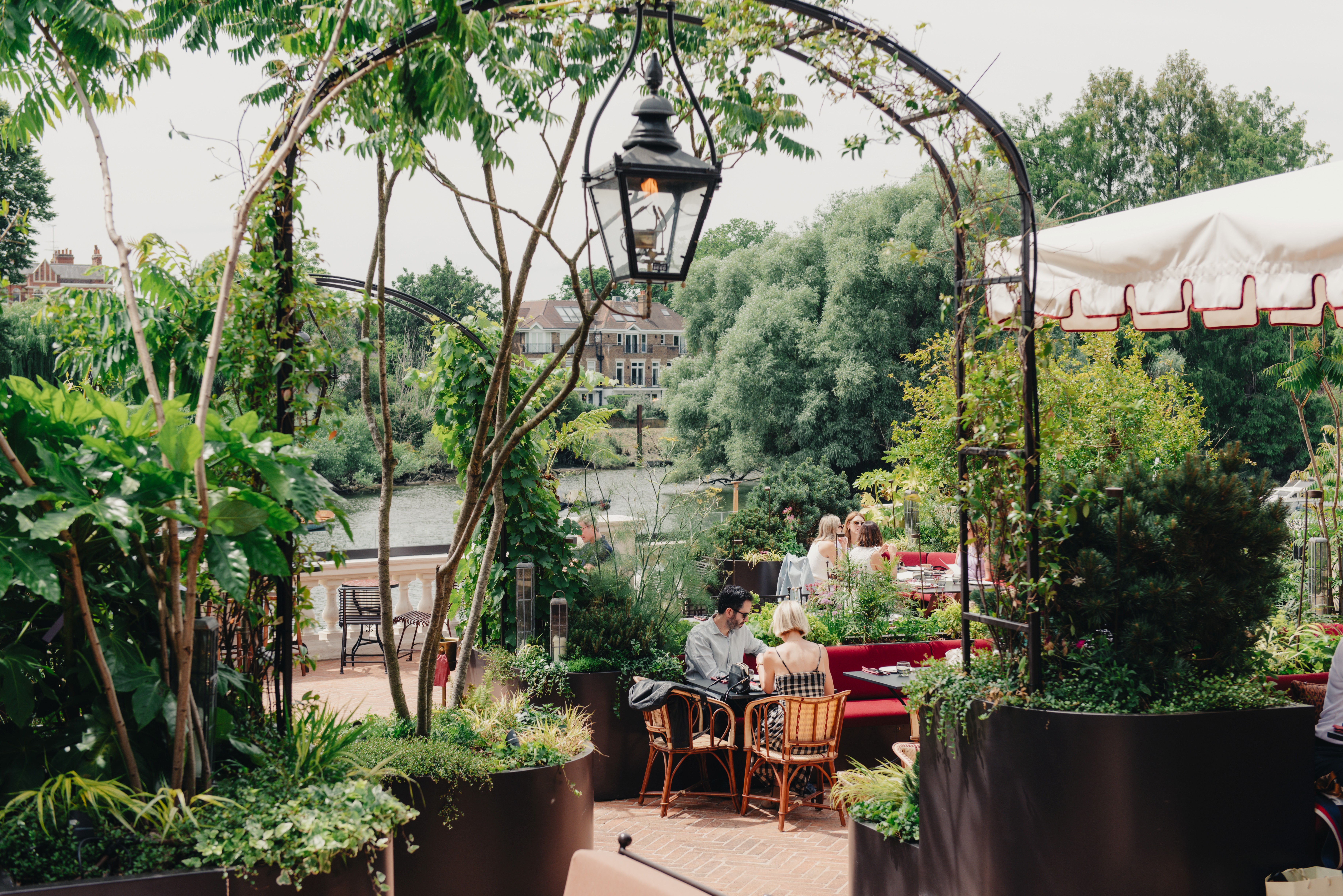 A restaurant with bold, petrol green-tinted interiors brought to life by intricate floral wallpapers, soft golden lighting, plush textiles, and a just as beautiful outdoor terrace.