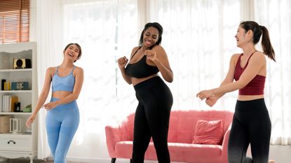 Women in workout gear dancing in a living room