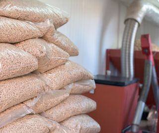 bags of wood pellets stacked up next to red biomass boiler