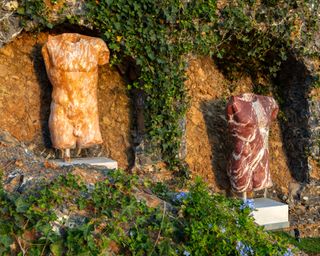 marble torso statues set in wall alcoves in mediterranean garden