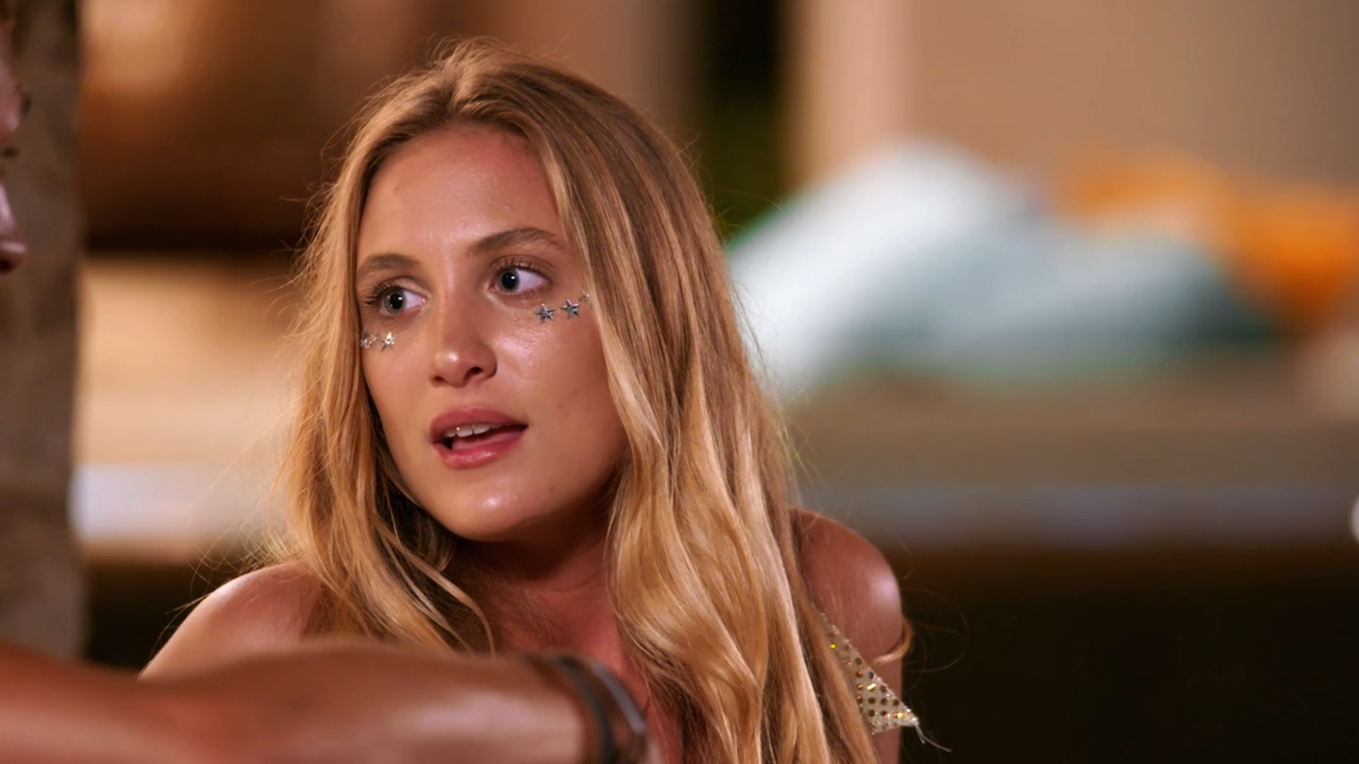 madison with stars on her face and wearing a gold top in a still from too hot to handle season 1