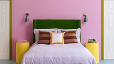 bedroom with pink walls and a green headboard and lilac sheets 