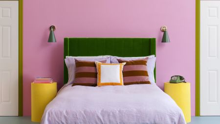 bedroom with pink walls and a green headboard and lilac sheets 