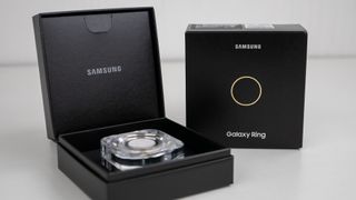 The gold Samsung Galaxy Ring with its box and charging case