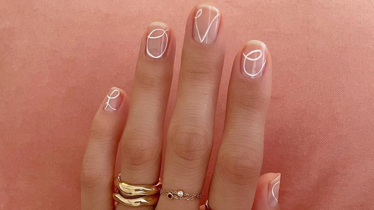 Womans hands with the word love written on them - valentines nails